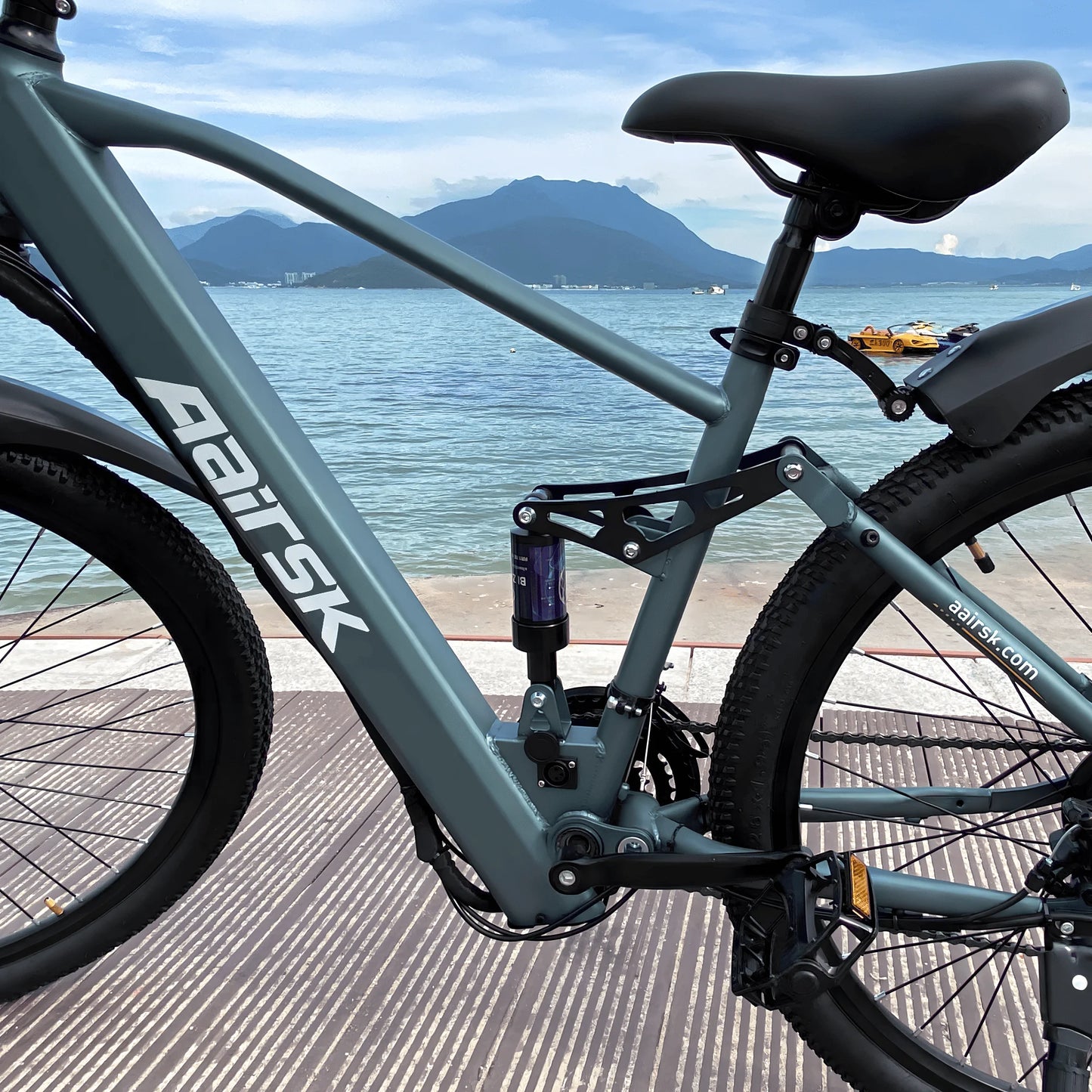 Bicycle with 'Aeisk' branding near a waterfront with mountains in the background
