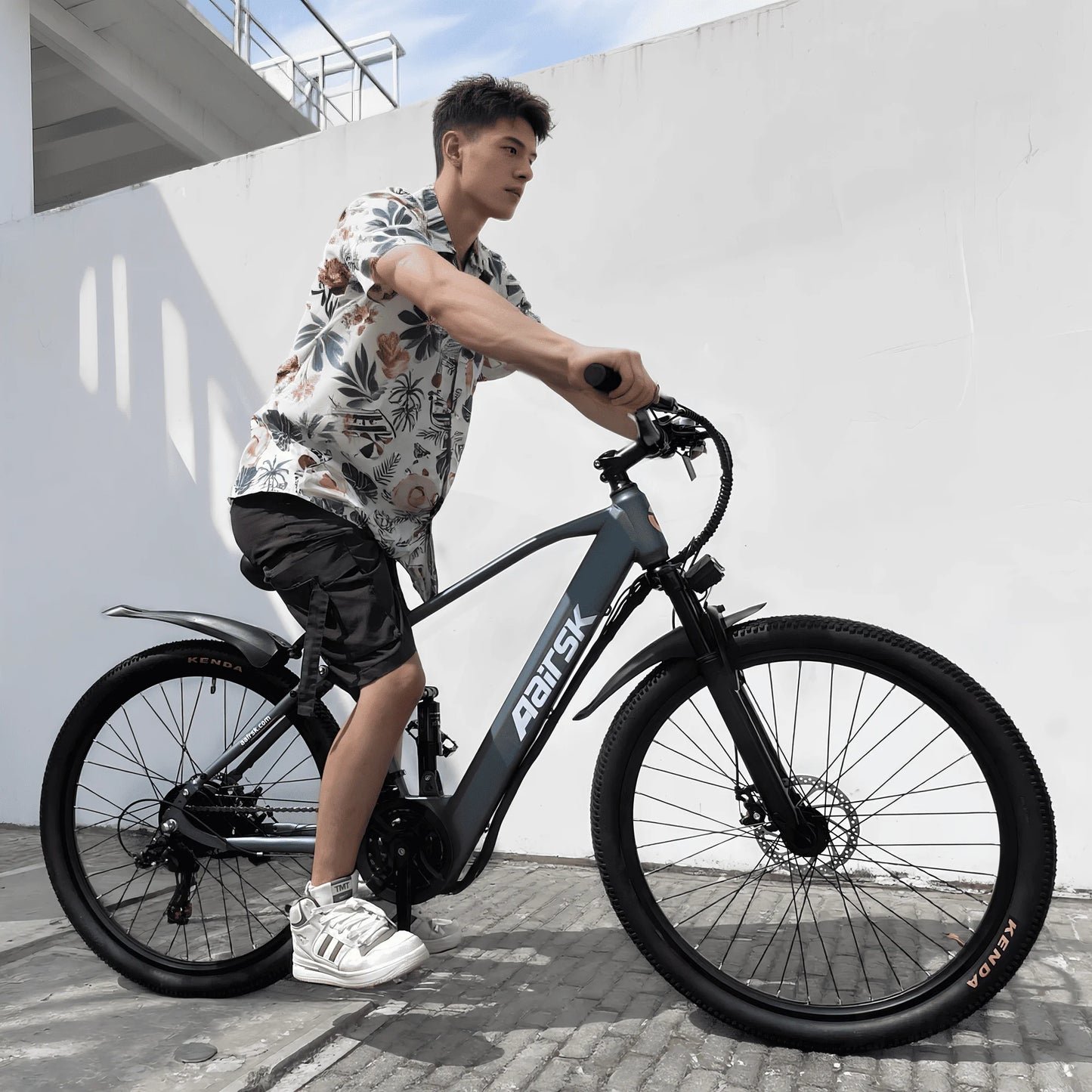 Person riding a black electric bike with a white wall in the background