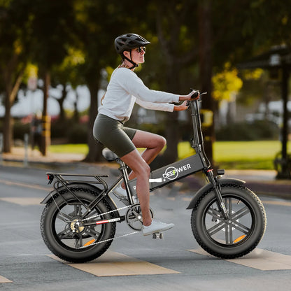 Woman riding IDOTATA 1000W Electric Bike 48V 20AH with fat tires on urban street, showcasing its folding design and style.