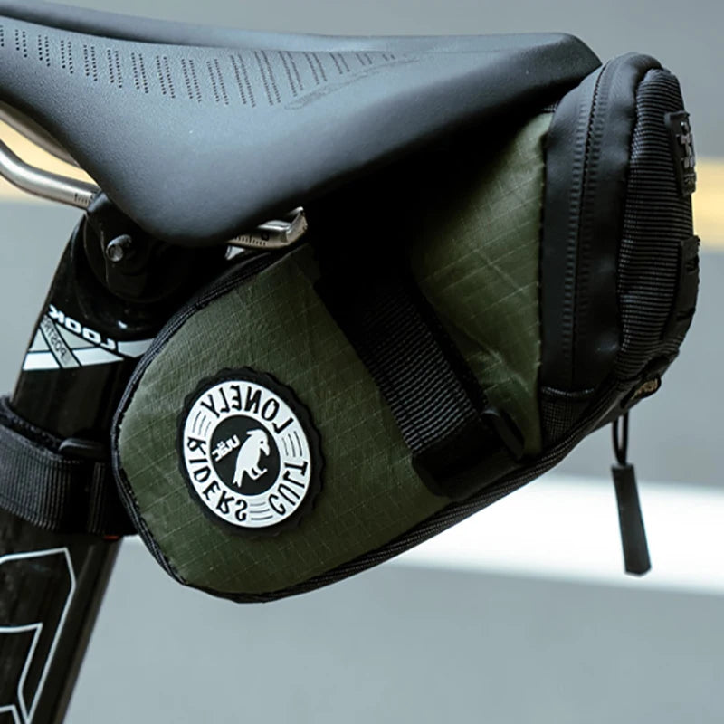 Green bike saddle bag with a brand logo attached to a bicycle seat.